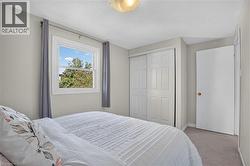 White framed window, light gray wall paint, off-white ceiling, paneled bi-fold closet doors, and light brown carpet - 
