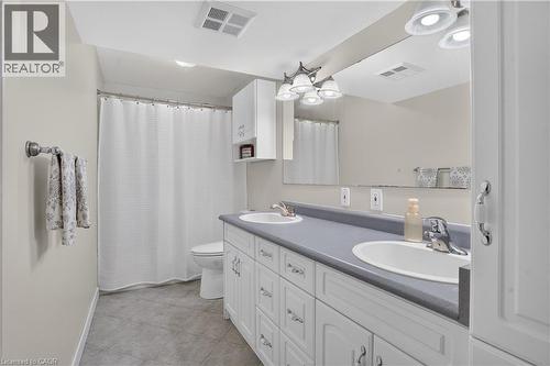 Dual vanity with integrated sinks, white cabinetry, and tile flooring - 38 Meadow Woods Crescent, Kitchener, ON 