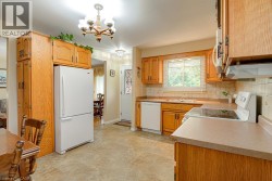 Wood-finish cabinetry and trim, neutral countertops, tile flooring, and white appliances including a refrigerator, dishwasher, and electric range - 