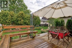 Wood deck with built-in bench, lush landscaping, and mature trees - 