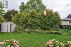 Manicured lawn with a garden bed featuring established plantings and mature trees - 