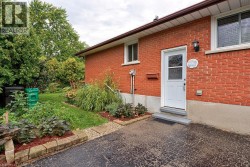 Red brick exterior featuring white trim windows and a white entry door - 