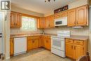 Kitchen featuring wood-finish cabinetry, built-in microwave, white electric range, and a double-basin sink - 210 Shelley Drive, Kitchener, ON 