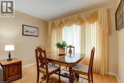Hardwood flooring, neutral wall color, large window with elegant drapery - 