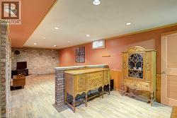 Recessed lighting, wood-finish flooring, exposed brick accent wall, wainscoting, and a built-in partial wall - 