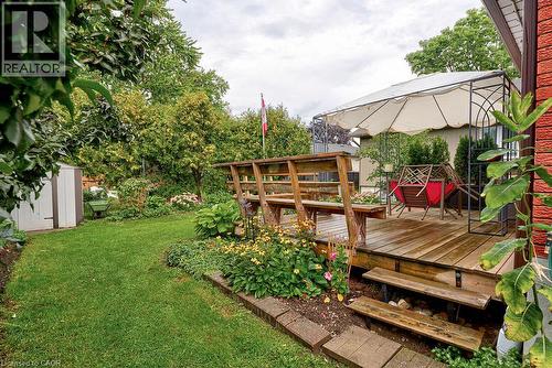Expansive backyard featuring a wood deck, built-in benches, and garden beds - 210 Shelley Drive, Kitchener, ON 