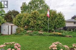 Manicured lawn with a garden bed featuring established plantings and mature trees - 