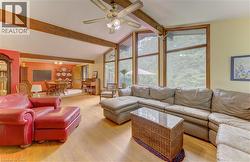 Vaulted ceiling with exposed wood beams, wood-finish flooring, and expansive windows - 