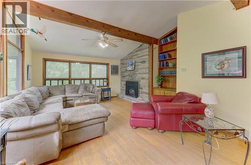 Vaulted ceiling with exposed wood beams, hardwood flooring, stone-clad fireplace, built-in shelving, and large windows - 80 Chapel Hill Drive, Kitchener, ON 