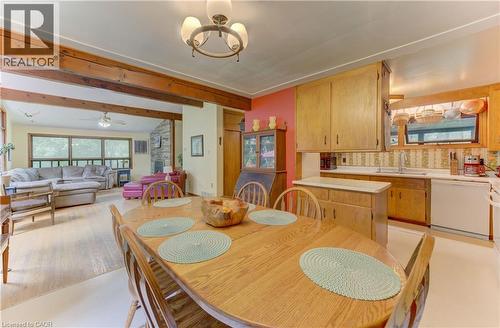 Exposed wood beams, light wood-finish flooring, a stone-faced fireplace, a ceiling fan, and ample natural light - 80 Chapel Hill Drive, Kitchener, ON 