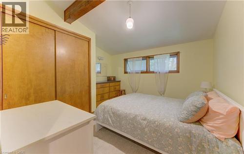Bedroom featuring a vaulted ceiling with exposed wood beams, wood-finish sliding closet doors, and multiple windows - 80 Chapel Hill Drive, Kitchener, ON 