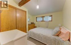 Bedroom featuring a vaulted ceiling with exposed wood beams, wood-finish sliding closet doors, and multiple windows - 