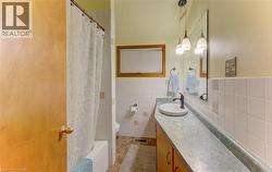Full bathroom featuring a single vanity with an integrated basin, a wall-mounted mirror, and a tub with a shower - 