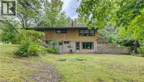 Expansive rear yard with mature trees, lower-level walkout access, and a multi-level concrete retaining wall - 80 Chapel Hill Drive, Kitchener, ON 