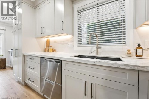 Light-toned wood-finish flooring complements custom shaker-style cabinetry with dark hardware - 1261 Stephenson Drive, Burlington, ON 