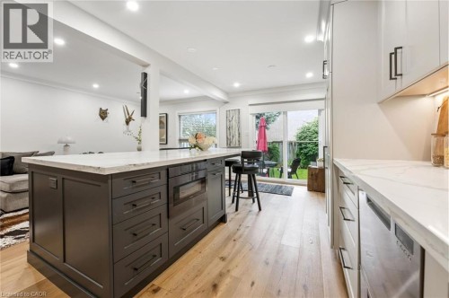 Kitchen island with integrated microwave, wood-finish flooring, recessed lighting, white countertops, and sliding glass doors to the exterior - 1261 Stephenson Drive, Burlington, ON 