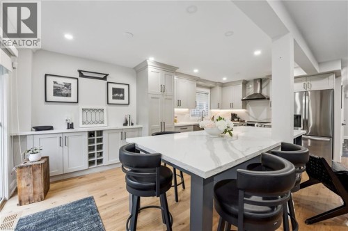 Gourmet kitchen featuring a large island with a stone countertop, stainless steel appliances, light cabinetry, and wood-finish flooring - 1261 Stephenson Drive, Burlington, ON 