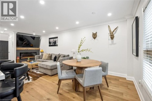 Recessed lighting, wood-finish flooring, white crown molding, wall-mounted electric fireplace with wood mantel, and white interior paint - 1261 Stephenson Drive, Burlington, ON 