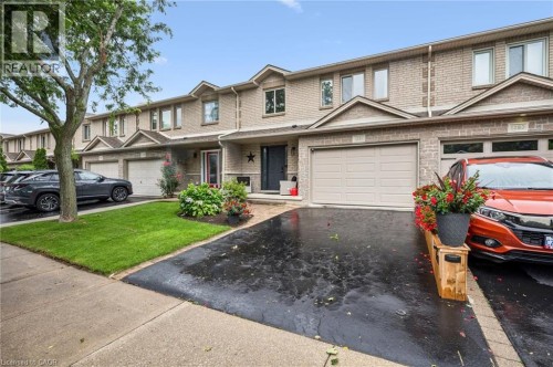 Brick exterior, attached garage, paved driveway, mature tree, and landscaped garden beds - 1261 Stephenson Drive, Burlington, ON 