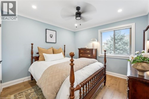 Wood-finish flooring, light blue wall paint, a window with blinds, a ceiling fan with integrated lighting, and recessed ceiling lights - 1261 Stephenson Drive, Burlington, ON 