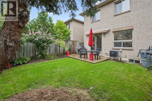 Brick exterior, ground-level patio, expansive lawn, mature tree, and privacy fencing - 1261 Stephenson Drive, Burlington, ON 