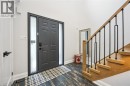 Entryway featuring a dark paneled door with frosted sidelights, a natural wood staircase with black iron balusters, and distressed wood-finish flooring - 1261 Stephenson Drive, Burlington, ON 
