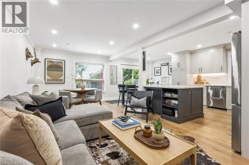 Open-concept living space featuring wood-finish flooring, recessed lighting, and a kitchen island with integrated shelving - 1261 Stephenson Drive, Burlington, ON 