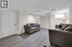 Living area featuring wood finished floors, a drop ceiling, and baseboards - 