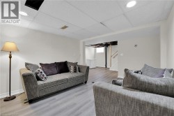 Living area featuring wood finished floors, baseboards, a drop ceiling, and recessed lighting - 