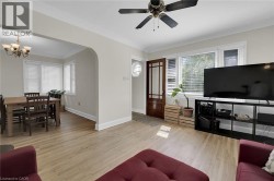 Living area with a chandelier, wood finished floors, crown molding, baseboards, and a ceiling fan - 