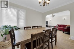Dining space with arched walkways, a chandelier, light wood-style flooring, crown molding, and a ceiling fan - 