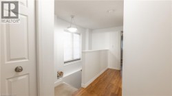 Hall with baseboards, an upstairs landing, and wood finished floors - 