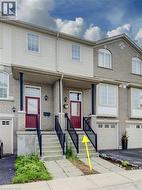 Welcoming brick and siding townhome featuring a defined front entrance with dual red doors, black iron railings, and concrete stoops - 