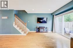 Wood-finish flooring, staircase with carpeted treads and wooden railing, recessed ceiling lighting, and expansive sliding glass doors - 