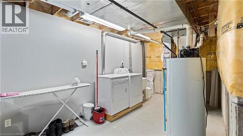 Laundry area featuring a water heater, exposed utility piping, and a washer and dryer - 124 Osborn Avenue, Brantford, ON 