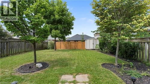 Expansive backyard featuring a manicured lawn, established trees, wood fencing, and a storage shed - 124 Osborn Avenue, Brantford, ON 