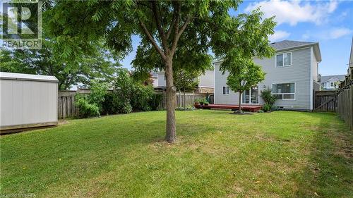 Expansive backyard featuring a manicured lawn, a detached storage shed, a wood-finish deck, mature trees, and a full fence surround - 124 Osborn Avenue, Brantford, ON 