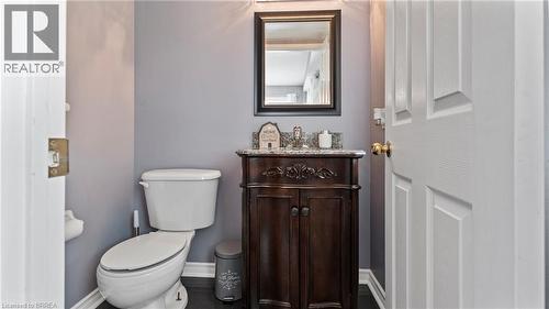 Powder room featuring a dark wood-finish vanity with a stone countertop, a framed mirror, and wood-finish flooring - 124 Osborn Avenue, Brantford, ON 