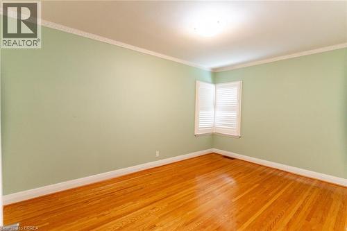 Hardwood flooring featuring a corner window with white plantation shutters, crown molding, and baseboards - 30 Proctor Avenue, Brantford, ON 