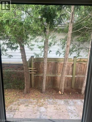 Private fenced backyard with mature trees and a paved patio - 30 Proctor Avenue, Brantford, ON 