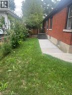 Red brick exterior with multiple windows, concrete walkway, and a concrete staircase featuring a metal handrail - 