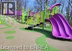 Purple and lime green playground structure with multiple slides and climbing elements - 