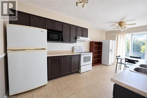 Kitchen featuring dark wood cabinetry, white tile backsplash, and light-toned countertops - 95 Resurrection Drive, Kitchener, ON 