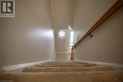 Carpeted staircase with wood handrail, leading to a tiled entry with a decorative octagonal window - 95 Resurrection Drive, Kitchener, ON 