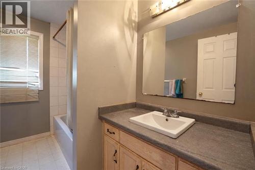 Bathroom featuring a single vanity with an integrated sink, a built-in mirror, and a tub with a shower enclosure - 95 Resurrection Drive, Kitchener, ON 
