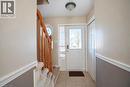 Tiled flooring entry with a white paneled door, natural wood staircase, and an octagonal window - 95 Resurrection Drive, Kitchener, ON 