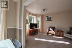 Spacious living area with dual glass doors providing natural light, carpeted flooring throughout, and entertainment-ready layout with television mounting - 