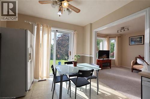 Kitchen with tile flooring and a ceiling fan, featuring a stainless steel refrigerator and a sliding glass door to the exterior - 95 Resurrection Drive, Kitchener, ON 