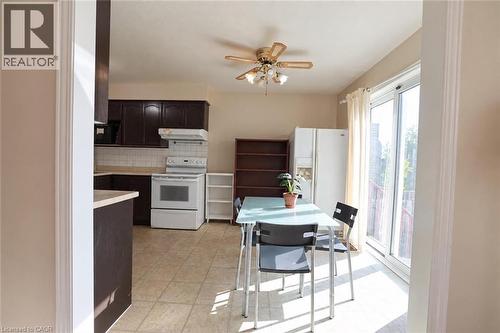 Kitchen with dark wood-finish cabinetry, white appliances, and tiled flooring - 95 Resurrection Drive, Kitchener, ON 
