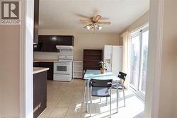 Kitchen with dark wood-finish cabinetry, white appliances, and tiled flooring - 